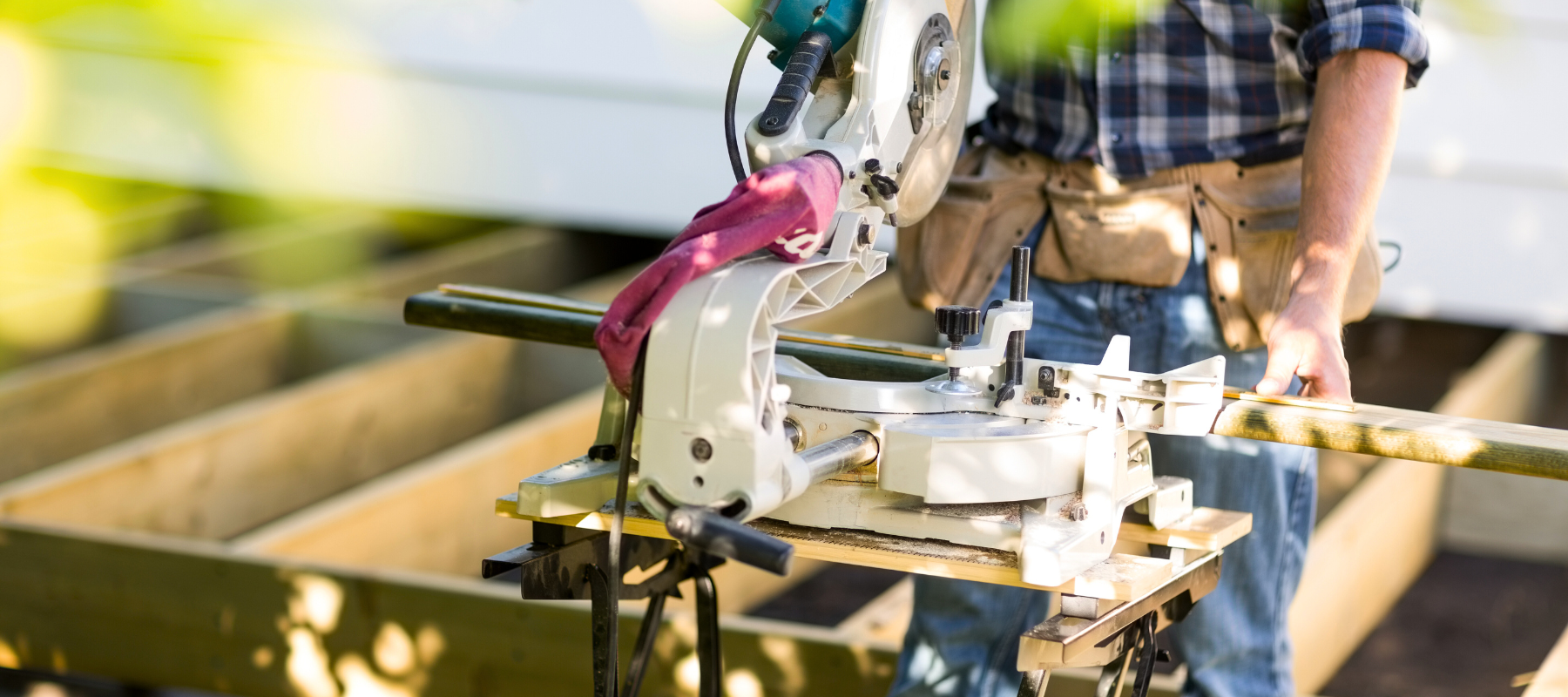 A contractor using a table saw outdoors to cut a piece of lumber