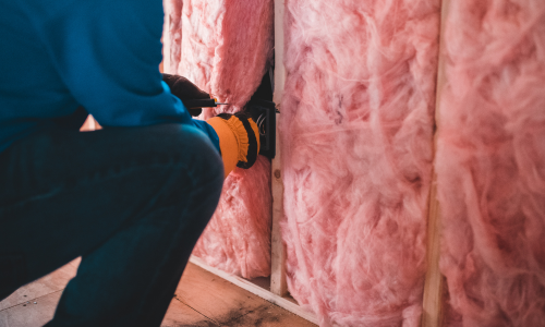 Pink insulation being rolled out and installed to a wall