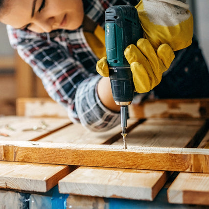 HardwareA contractor using a blue power drill to install a wood screw into a small piece of wood
