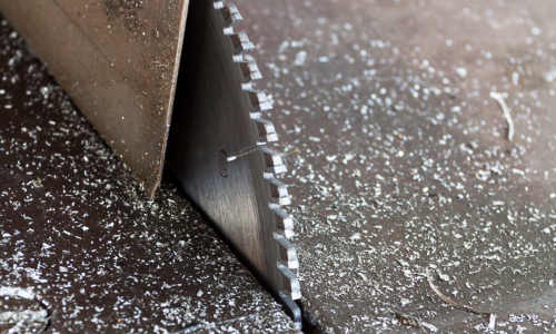 A close up of a table saw with metal shavings surrounding it